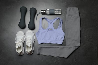 Photo of Sportswear, sneakers, dumbbells and water bottle on grey background, flat lay