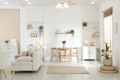 Photo of Stylish dining table with chairs and comfortable sofa in room. Interior design