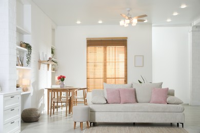 Photo of Stylish dining table with chairs and comfortable sofa in room. Interior design