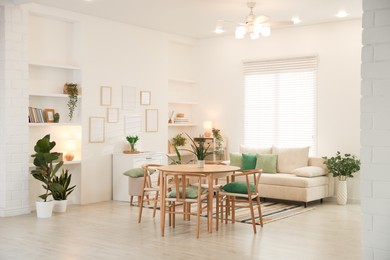 Photo of Stylish dining table with chairs and comfortable sofa in room. Interior design