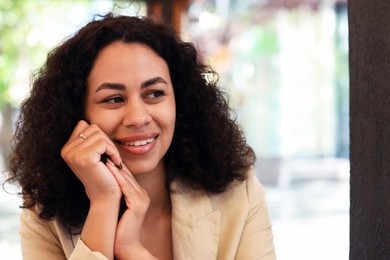 Photo of Portrait of smiling Latin American woman in cafe. Space for text
