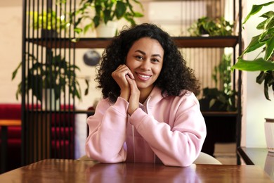Photo of Portrait of smiling Latin American woman at table in cafe
