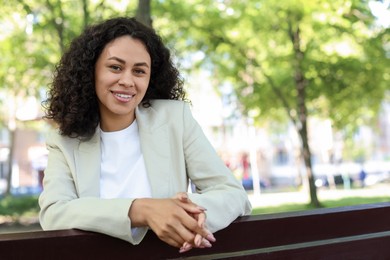 Photo of Portrait of smiling Latin American woman on bench outdoors