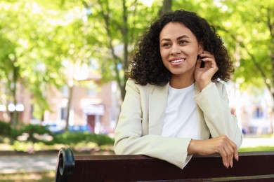 Photo of Portrait of smiling Latin American woman on bench outdoors. Space for text