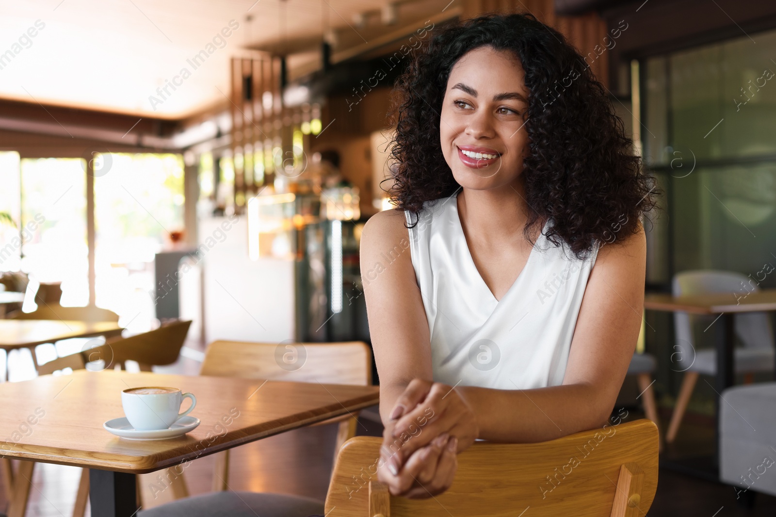 Portrait of smiling Latin American woman sitting on chair in cafe Photo of Portrait of smiling Latin American woman sitting on chair in cafe