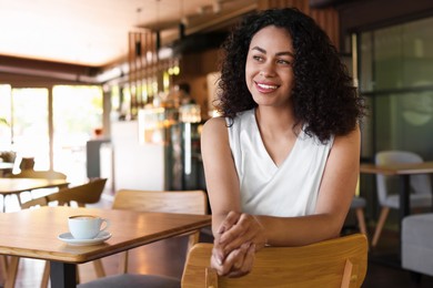Photo of Portrait of smiling Latin American woman sitting on chair in cafe