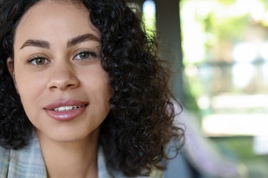 Photo of Portrait of smiling Latin American woman on blurred background, closeup. Space for text