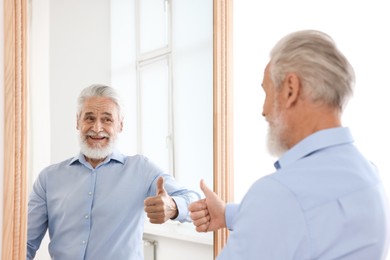 Photo of Handsome senior man showing thumbs up mirror indoors