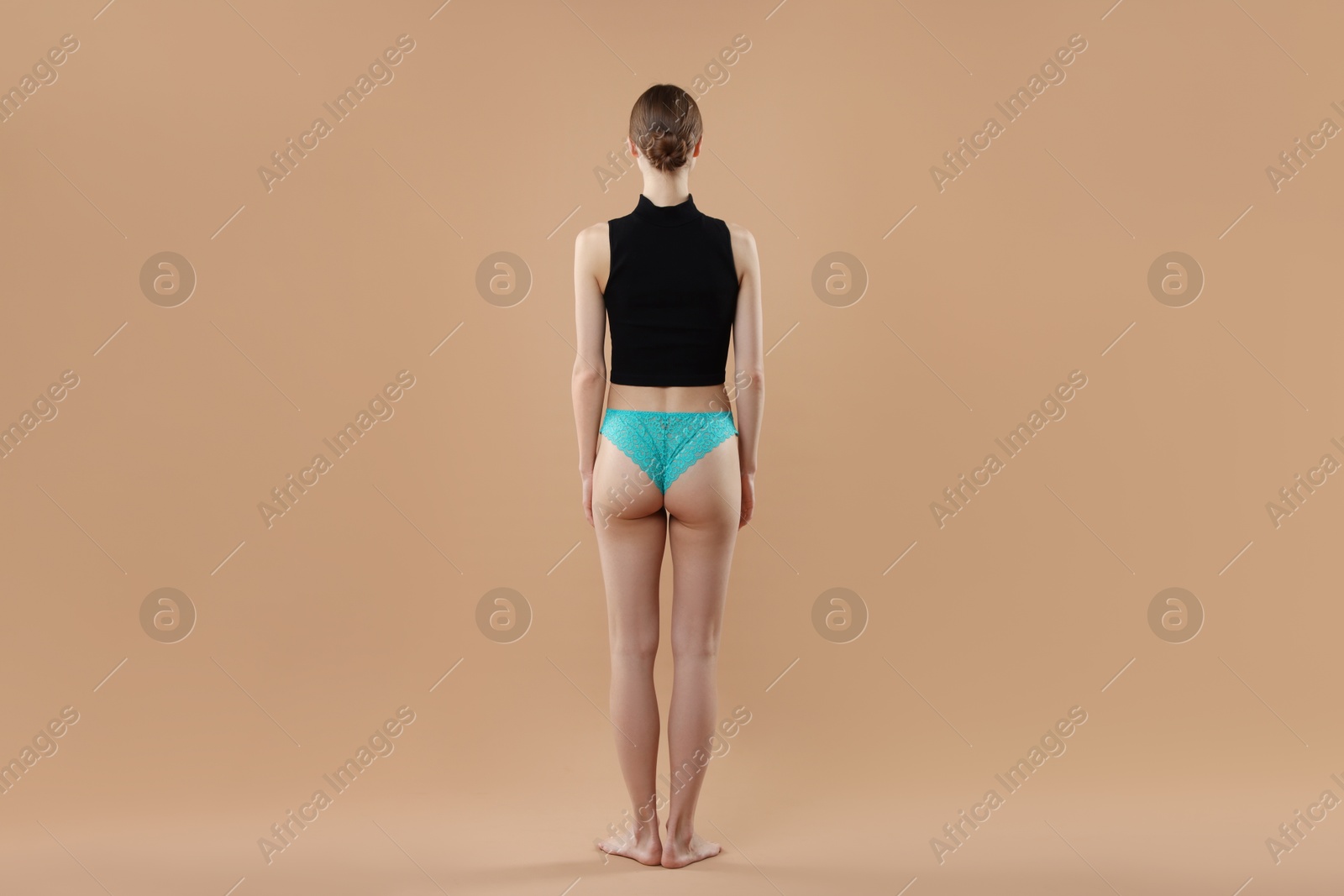 Woman wearing beautiful underwear on beige background, back view Photo of Woman wearing beautiful underwear on beige background, back view