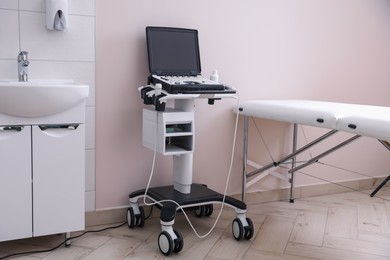 Photo of Modern ultrasound machine, sink and examination bed in clinic