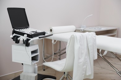 Photo of Modern ultrasound machine and examination bed in clinic