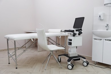 Photo of Modern ultrasound machine and examination bed in clinic