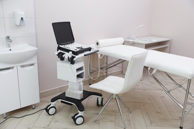 Photo of Modern ultrasound machine and examination bed in clinic