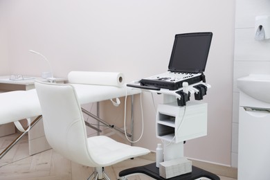 Photo of Modern ultrasound machine and examination bed in clinic