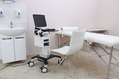 Photo of Modern ultrasound machine and examination bed in clinic