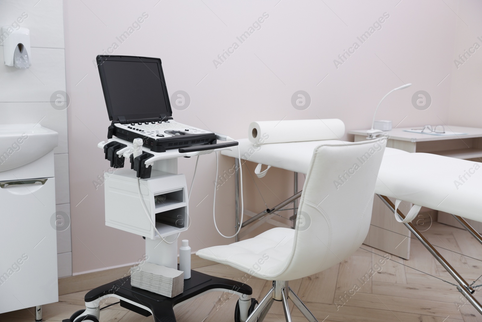 Modern ultrasound machine and examination bed in clinic Photo of Modern ultrasound machine and examination bed in clinic