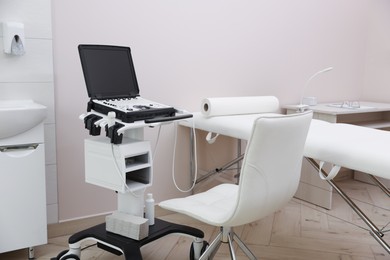 Photo of Modern ultrasound machine and examination bed in clinic