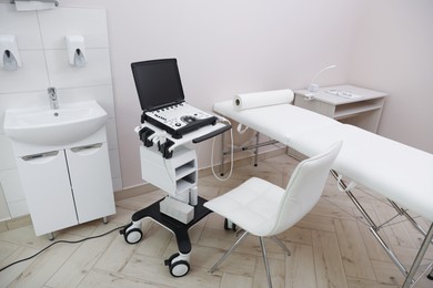 Photo of Modern ultrasound machine and examination bed in clinic, above view