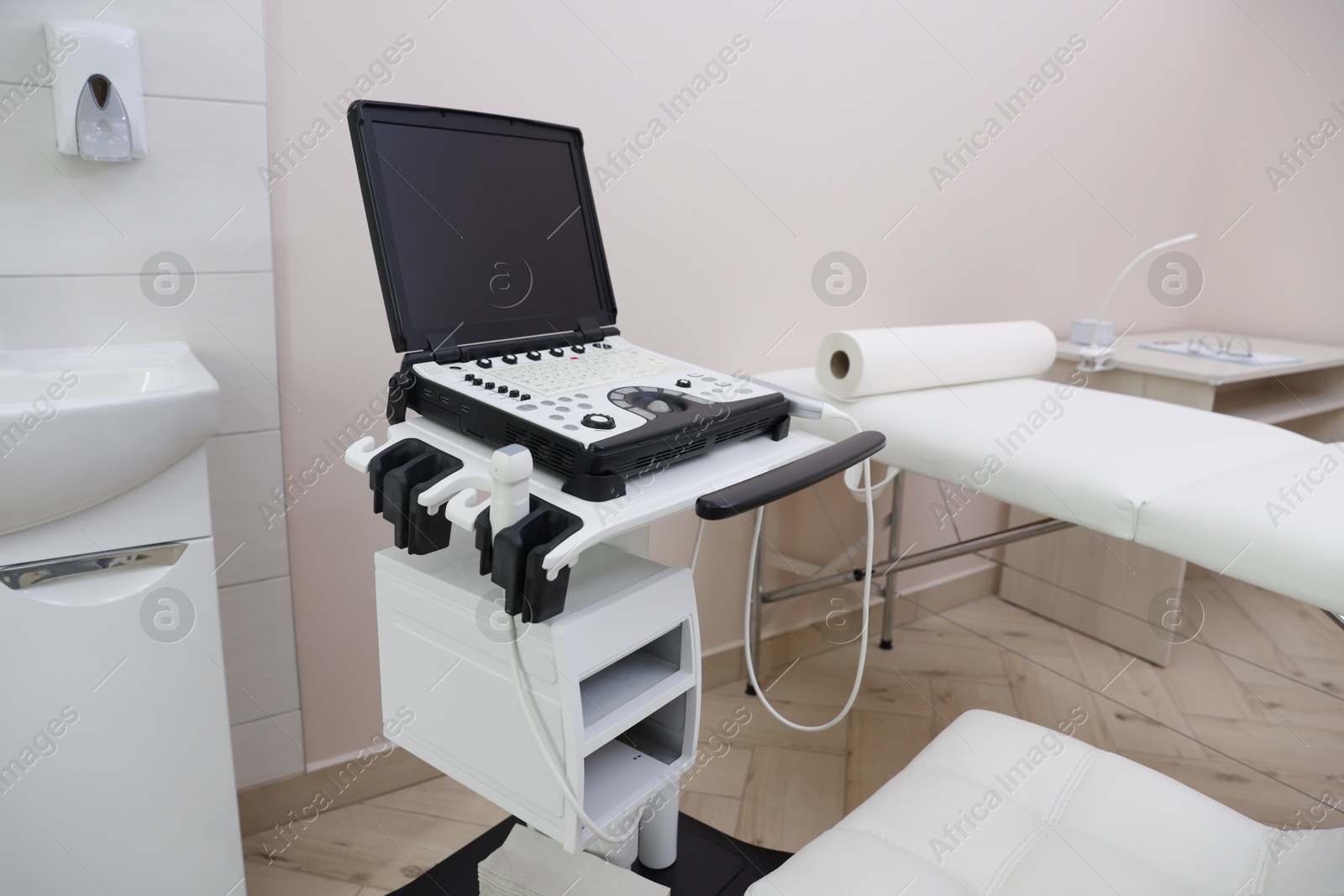 Modern ultrasound machine and examination bed in clinic Photo of Modern ultrasound machine and examination bed in clinic