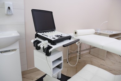 Photo of Modern ultrasound machine and examination bed in clinic