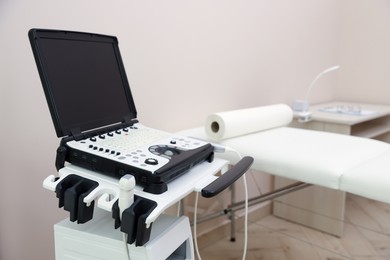 Photo of Modern ultrasound machine and examination bed in clinic