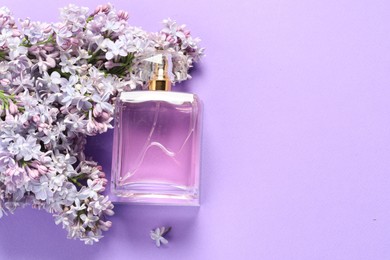 Photo of Bottle with perfume and lilac flowers on violet background, flat lay. Space for text