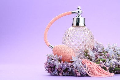 Photo of Bottle with perfume and lilac flowers on violet gradient background, closeup. Space for text