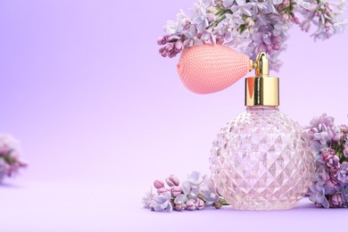 Photo of Bottle with perfume and lilac flowers on violet gradient background, closeup. Space for text