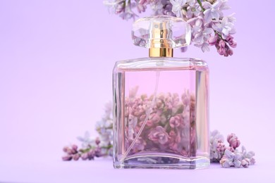 Photo of Bottle with perfume and lilac flowers on violet gradient background, closeup. Space for text