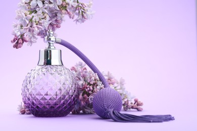 Photo of Bottle with perfume and lilac flowers on violet gradient background, closeup