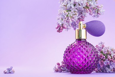 Photo of Bottle with perfume and lilac flowers on violet gradient background, closeup. Space for text