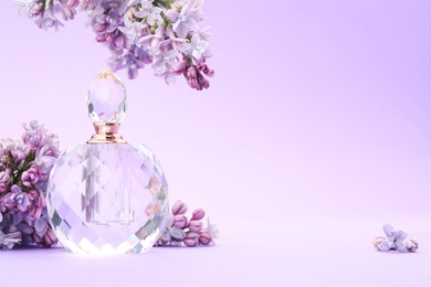 Photo of Bottle with perfume and lilac flowers on violet gradient background, closeup. Space for text