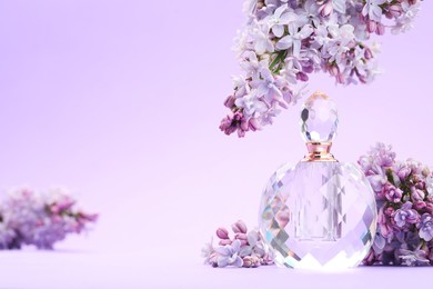 Photo of Bottle with perfume and lilac flowers on violet gradient background, closeup. Space for text