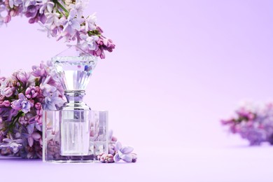 Photo of Bottle with perfume and lilac flowers on violet gradient background, closeup. Space for text