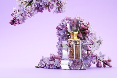 Photo of Bottle with perfume and lilac flowers on violet gradient background, closeup