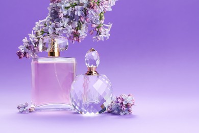 Photo of Bottles with perfumes and lilac flowers on purple gradient background, closeup. Space for text