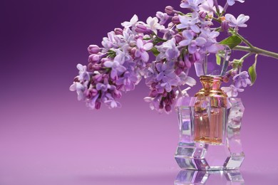 Photo of Bottle of perfume and branch with lilac flowers on mirror surface against color gradient background, closeup. Space for text