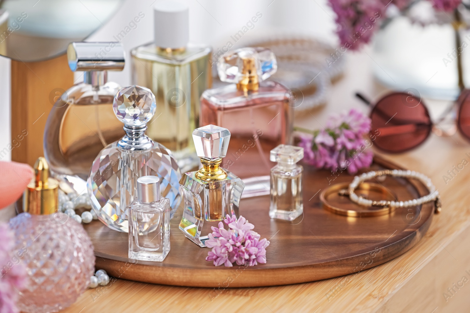 Bottles with perfumes, lilac flowers and accessories on wooden table indoors, closeup Photo of Bottles with perfumes, lilac flowers and accessories on wooden table indoors, closeup
