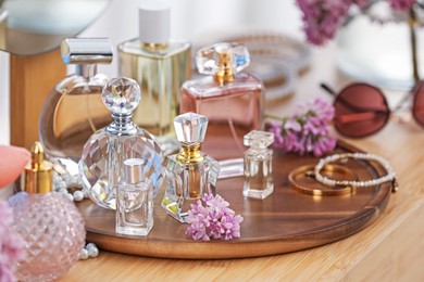 Photo of Bottles with perfumes, lilac flowers and accessories on wooden table indoors, closeup