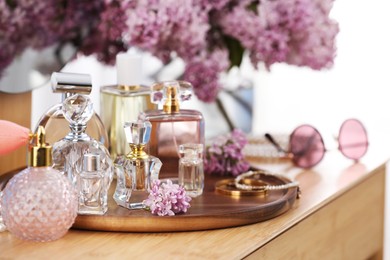 Photo of Bottles with perfumes, lilac flowers and accessories on wooden table indoors, closeup