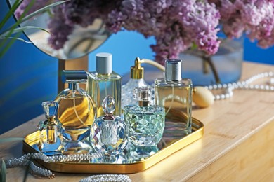 Photo of Bottles with perfumes, lilac flowers and accessories on dressing table indoors