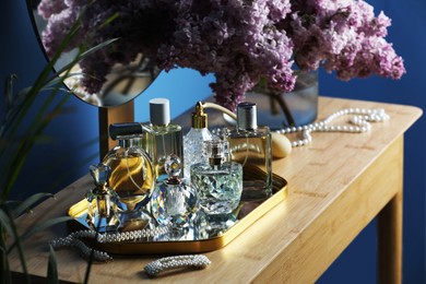 Photo of Bottles with perfumes, lilac flowers and accessories on dressing table indoors