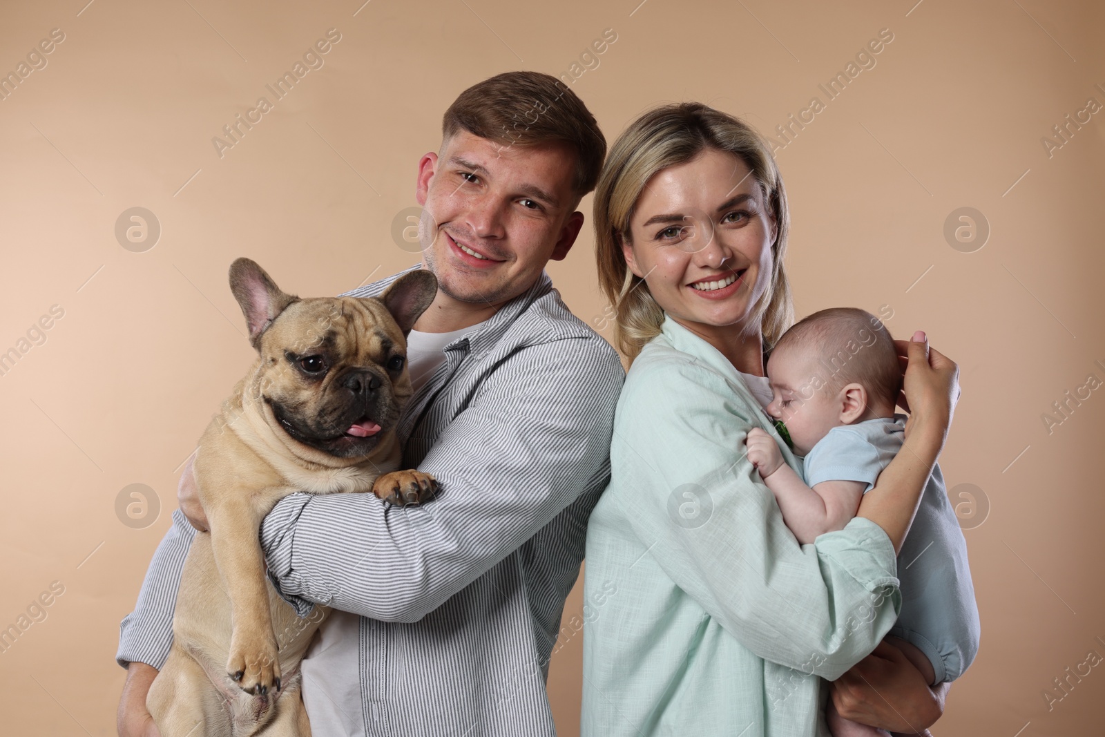 Happy family with little baby and cute dog on beige background Photo of Happy family with little baby and cute dog on beige background