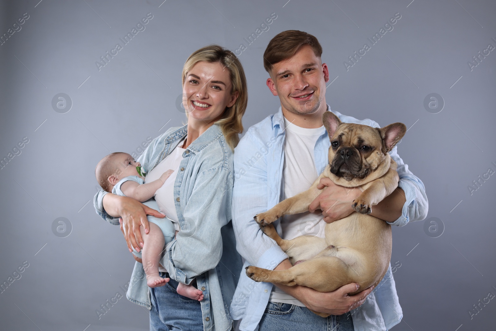 Happy family with little baby and cute dog on grey background Photo of Happy family with little baby and cute dog on grey background