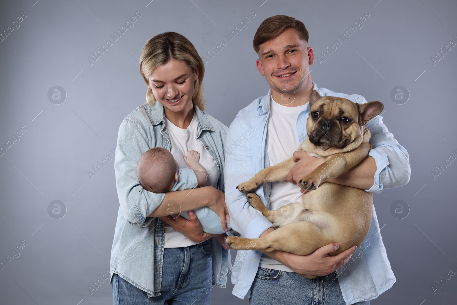Happy family with little baby and cute dog on grey background Photo of Happy family with little baby and cute dog on grey background