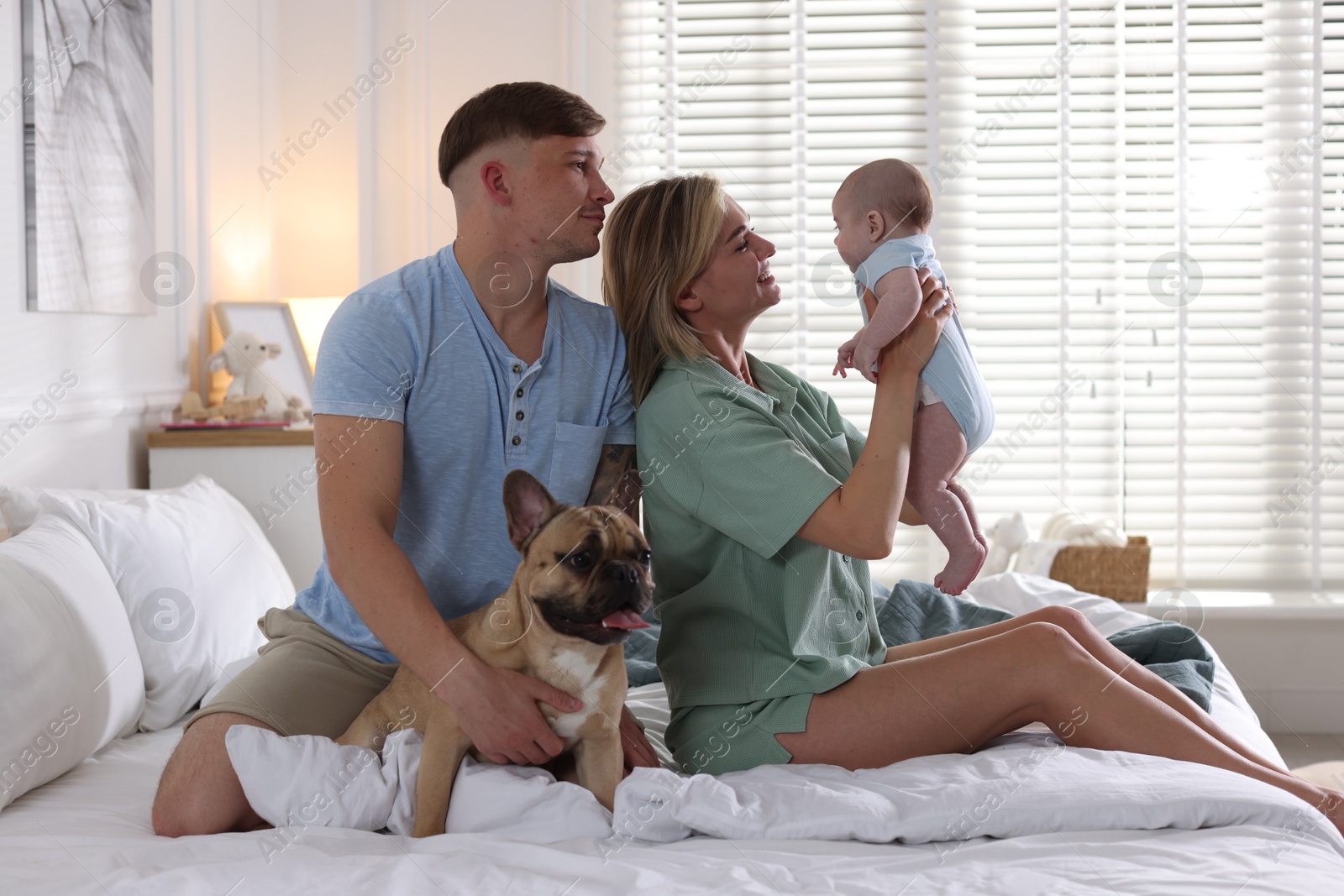 Happy family with little baby and cute dog on bed at home Photo of Happy family with little baby and cute dog on bed at home