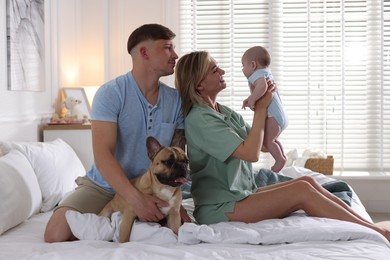 Photo of Happy family with little baby and cute dog on bed at home