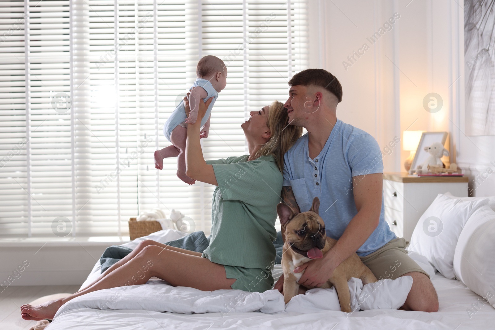 Happy family with little baby and cute dog on bed at home Photo of Happy family with little baby and cute dog on bed at home