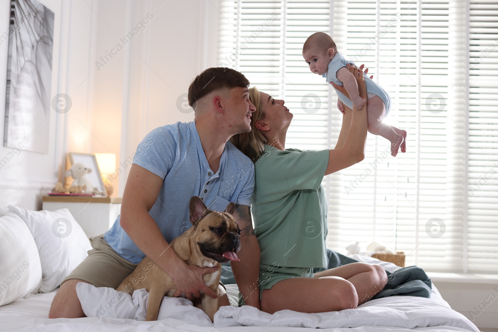 Happy family with little baby and cute dog on bed at home Photo of Happy family with little baby and cute dog on bed at home