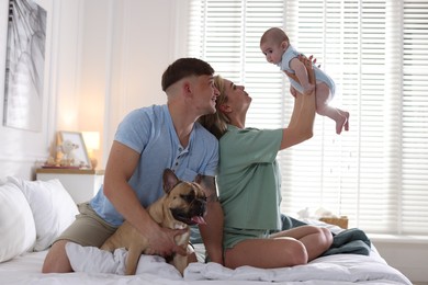 Photo of Happy family with little baby and cute dog on bed at home